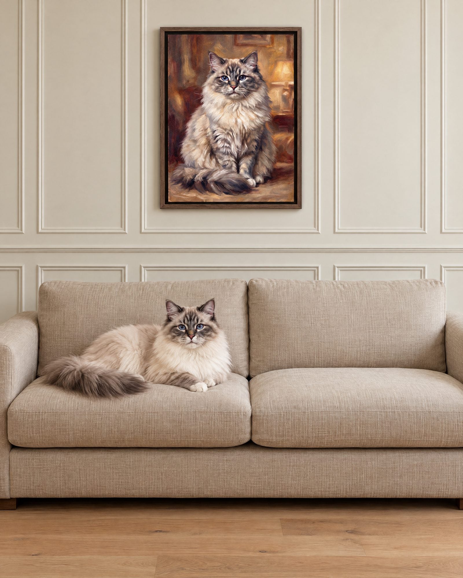 A long-haired ragdoll lying on a beige sofa beneath a framed oil portrait of a ragdoll.